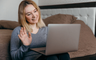 International student waving probably on a zoom to her friends or family on the computer